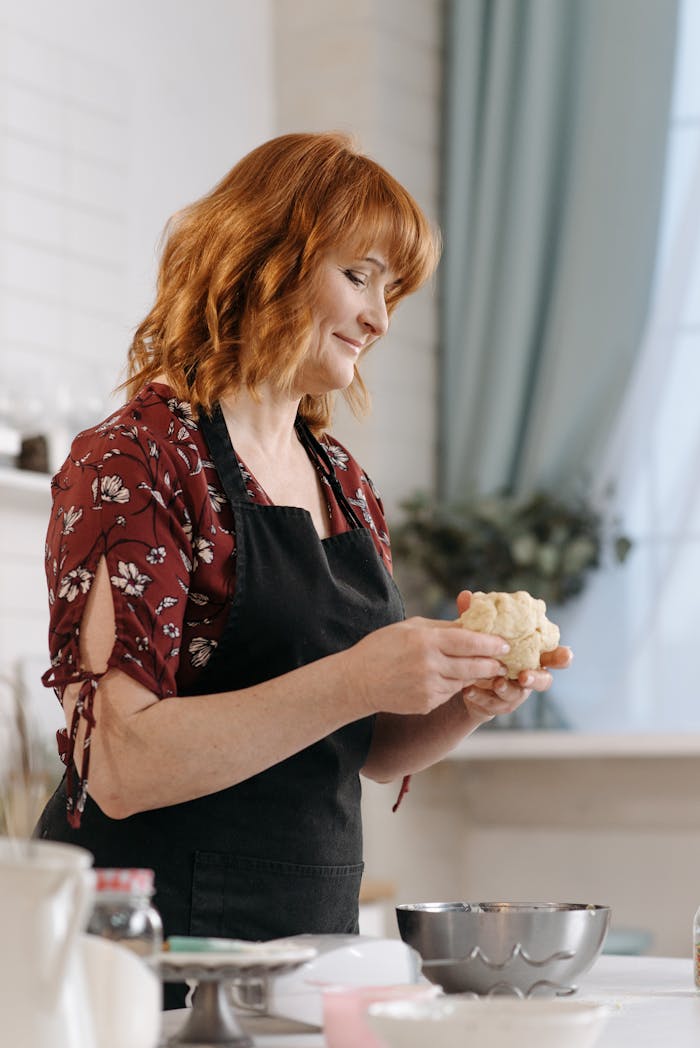 Woman holding dough, preparing to bake in a bright kitchen setting.
